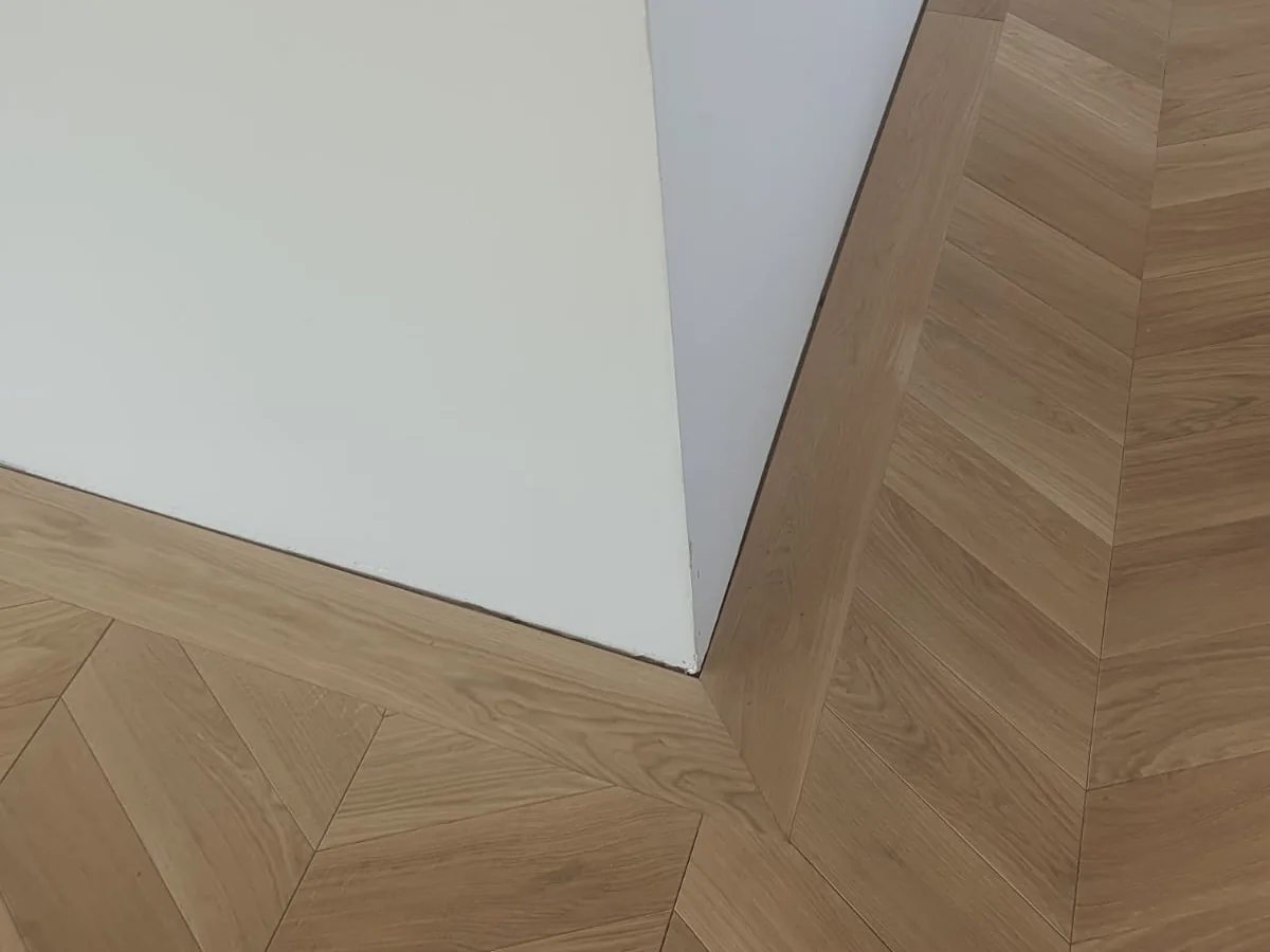 Detail napojenia chevron podlahy pri vnútornom rohu steny