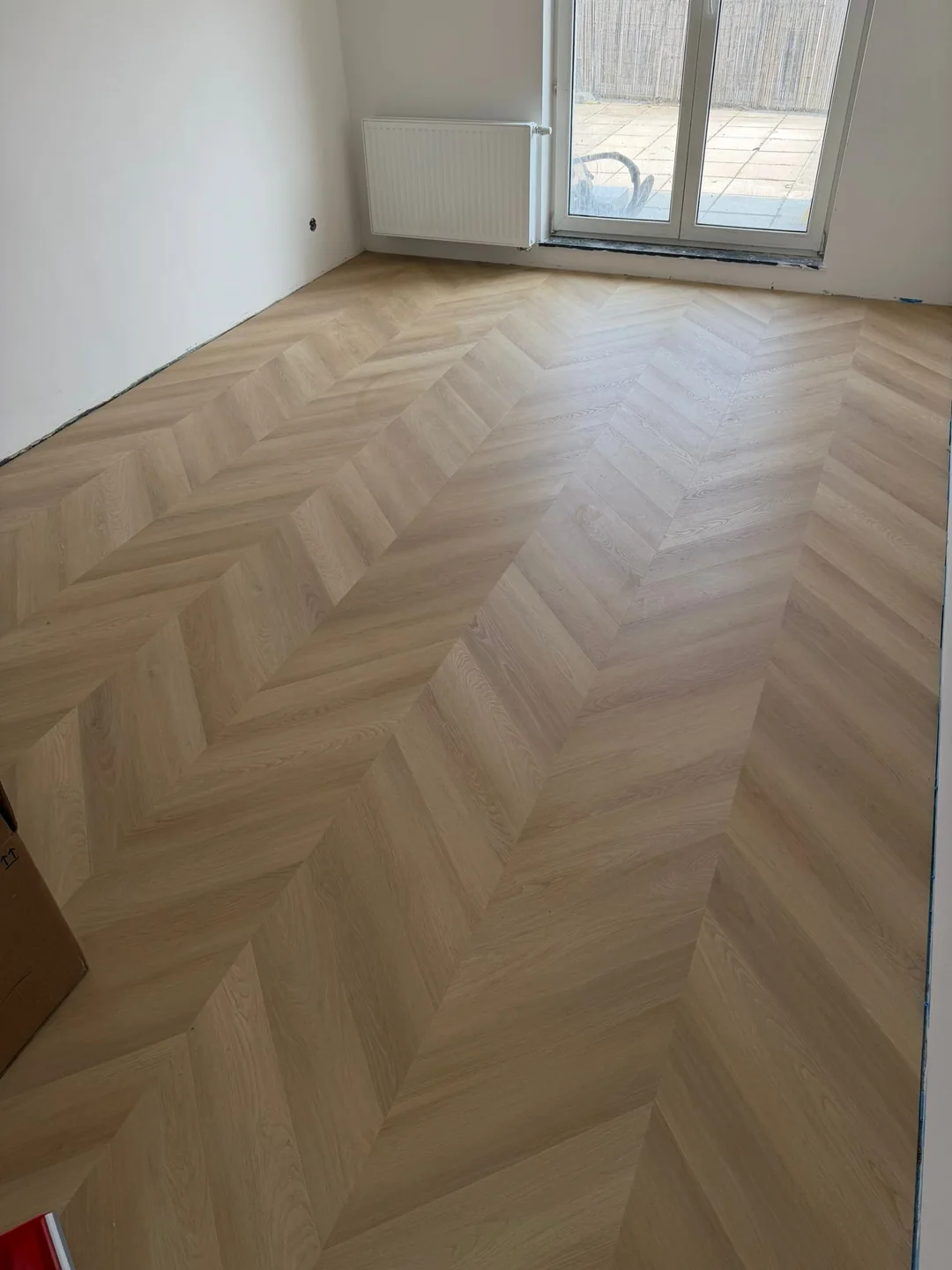 Svetlá podlaha chevron v miestnosti pri balkónových dverách