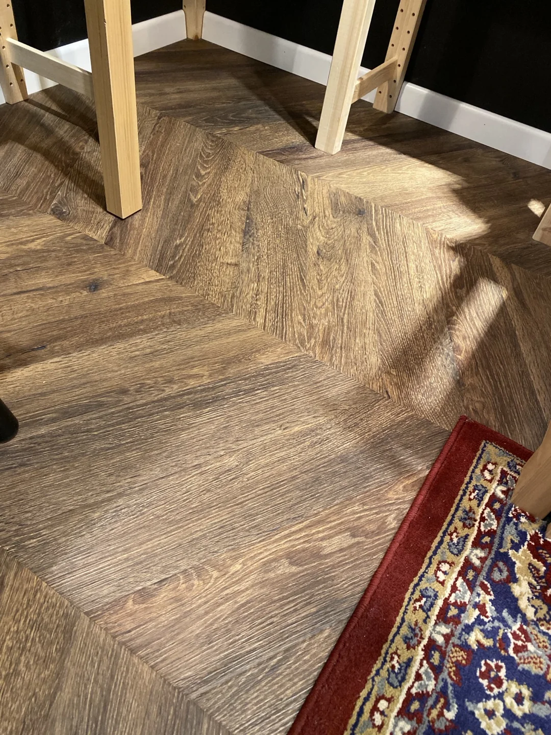 Detail tmavej podlahy chevron pri drevenom nábytku